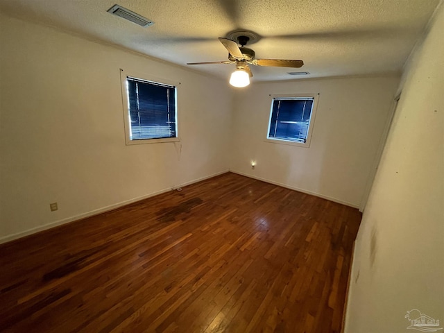 unfurnished room with ceiling fan, visible vents, a textured ceiling, and dark wood-style floors