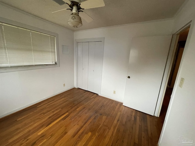 unfurnished bedroom with a closet, baseboards, hardwood / wood-style floors, and a ceiling fan