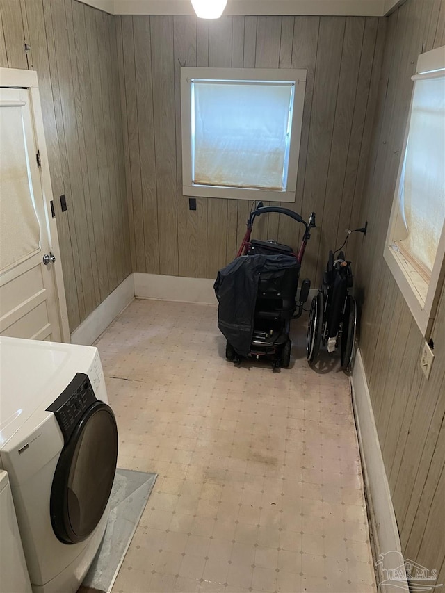 washroom with laundry area, wooden walls, light floors, and washing machine and clothes dryer