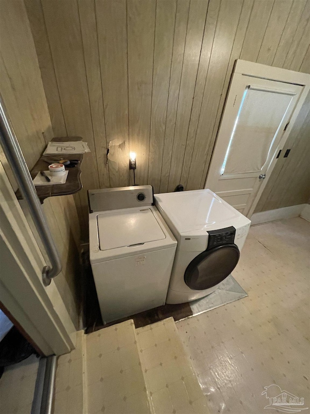 washroom featuring wooden walls, laundry area, and washing machine and clothes dryer