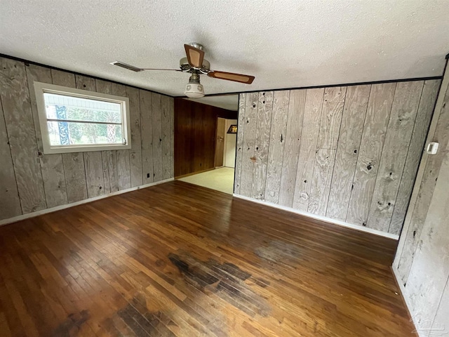 unfurnished room with visible vents, a ceiling fan, hardwood / wood-style flooring, a textured ceiling, and baseboards