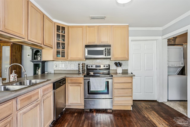 kitchen featuring light brown cabinetry, stainless steel appliances, a sink, and stacked washer and clothes dryer