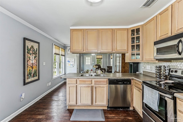 kitchen with light brown cabinetry, a sink, baseboards, a peninsula, and stainless steel appliances