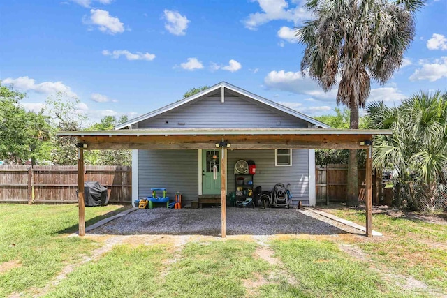 back of house with fence, a carport, a lawn, and driveway
