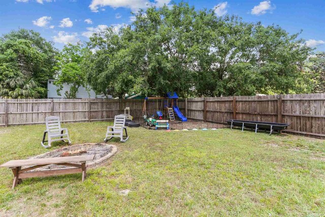view of yard with a fenced backyard, a playground, and an outdoor fire pit