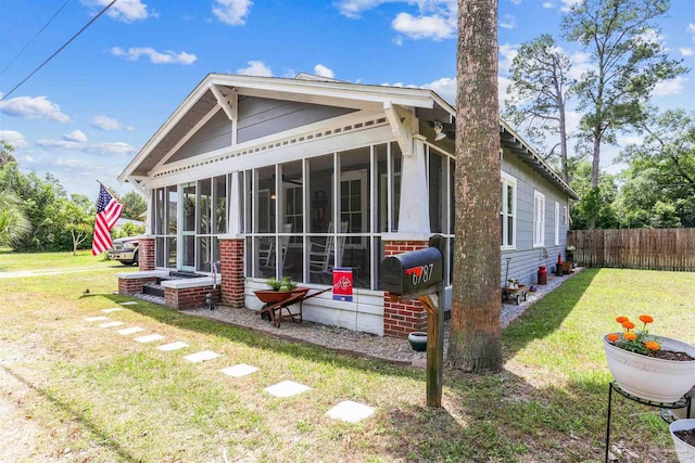 back of house featuring fence, a lawn, and a sunroom