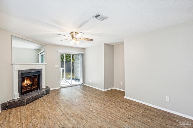 unfurnished living room featuring a fireplace, hardwood / wood-style floors, a textured ceiling, and ceiling fan