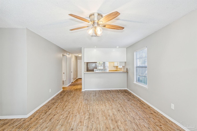 unfurnished living room featuring ceiling fan, a textured ceiling, and light hardwood / wood-style flooring