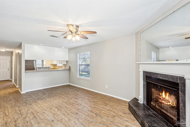 unfurnished living room featuring a fireplace, hardwood / wood-style floors, a textured ceiling, and ceiling fan