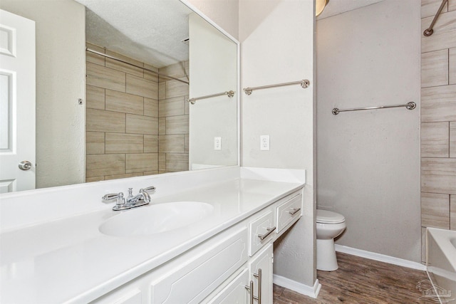 full bathroom featuring vanity, tiled shower / bath, hardwood / wood-style flooring, toilet, and a textured ceiling