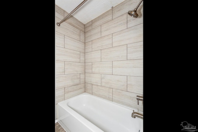 bathroom featuring tiled shower / bath combo and a textured ceiling