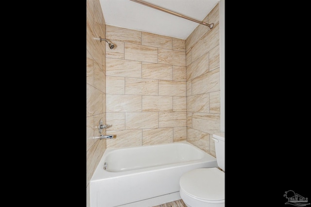 bathroom with tiled shower / bath combo and toilet