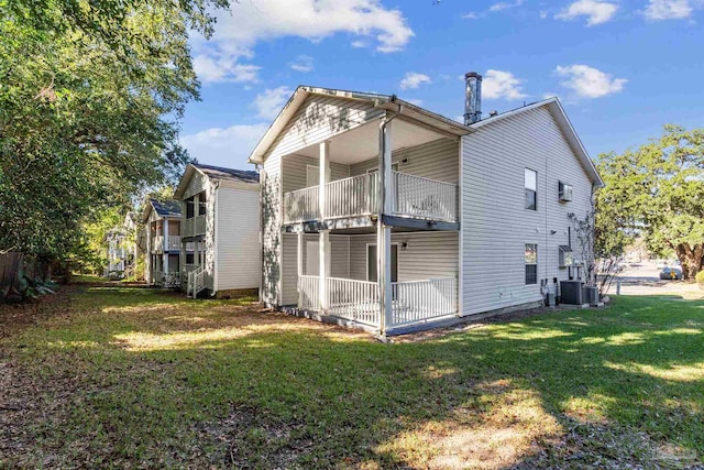 rear view of house with a balcony, central AC, and a lawn