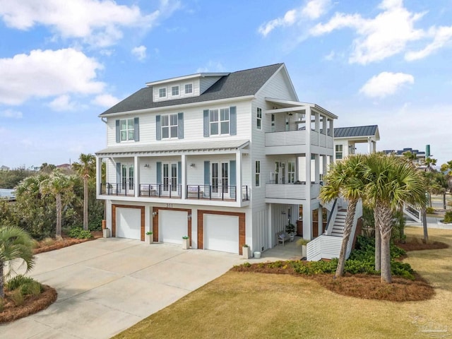 raised beach house with a balcony, a garage, driveway, french doors, and stairway