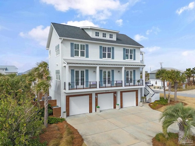 view of front of house with an attached garage, stairway, concrete driveway, and french doors