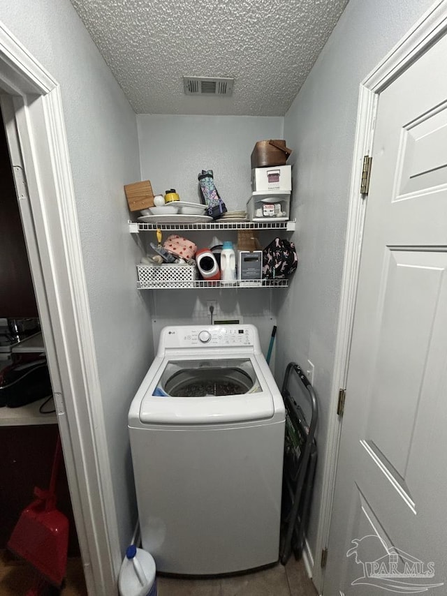 laundry area with laundry area, visible vents, washer / dryer, a textured ceiling, and tile patterned floors