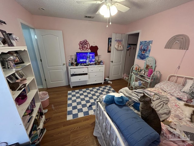 bedroom featuring a textured ceiling, ceiling fan, wood finished floors, and visible vents
