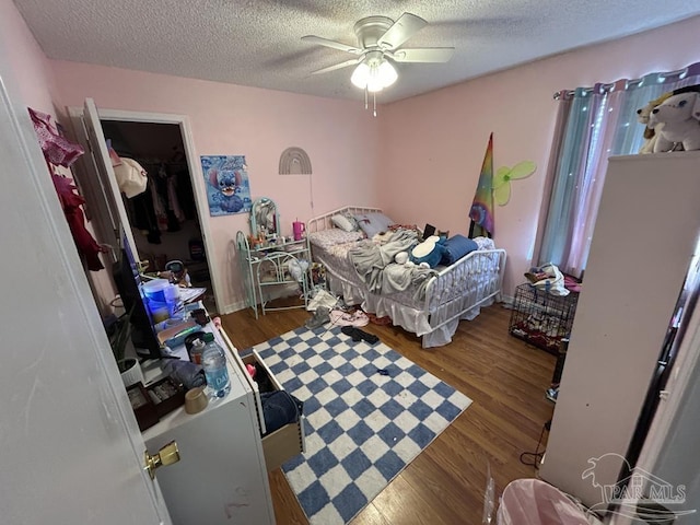 bedroom with a textured ceiling, ceiling fan, and wood finished floors