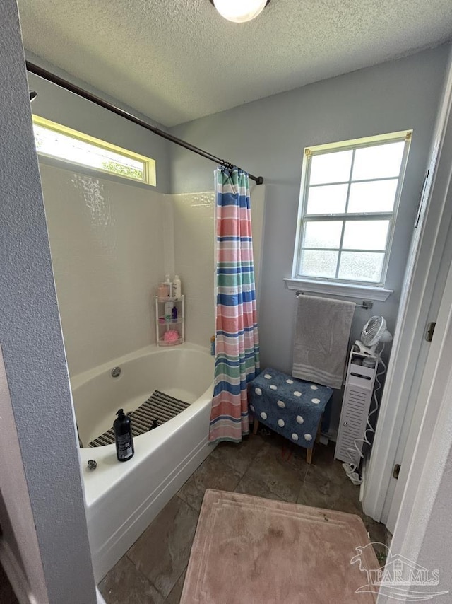 full bath with a healthy amount of sunlight, shower / bath combo with shower curtain, and a textured ceiling