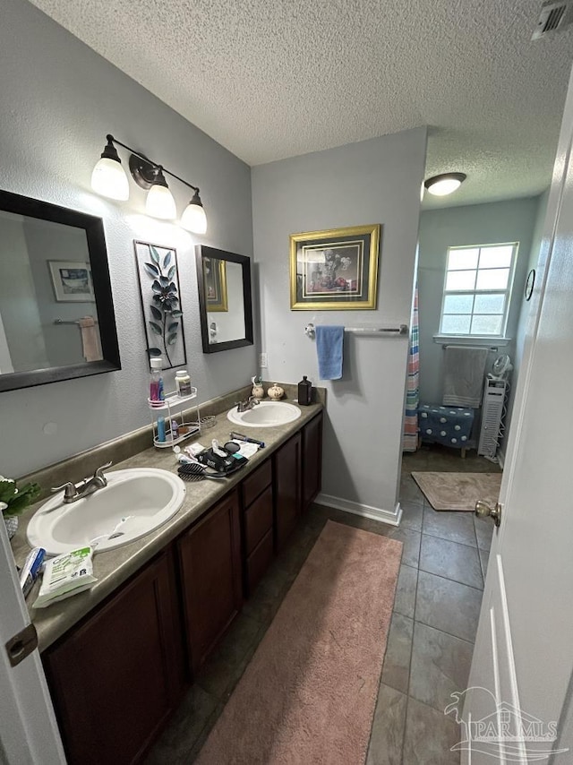 bathroom featuring a sink, a shower with curtain, double vanity, and a textured ceiling