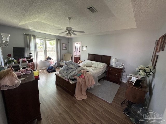 bedroom with dark wood-type flooring, a textured ceiling, ceiling fan, and visible vents