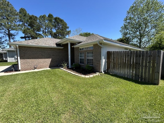 single story home with brick siding, fence, a shingled roof, and a front yard