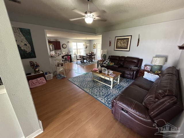 living area with a textured ceiling, ceiling fan, and wood finished floors
