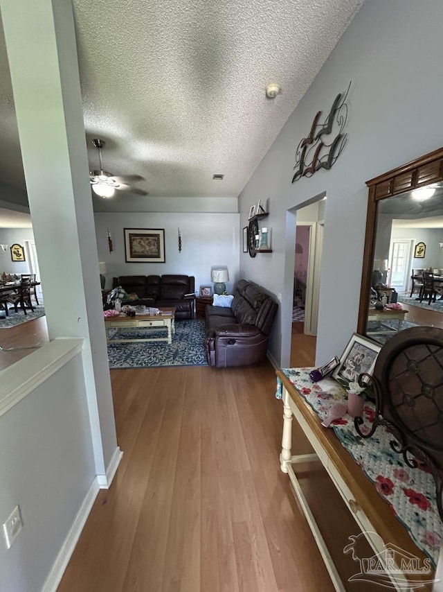 living area with visible vents, a textured ceiling, ceiling fan, and wood finished floors