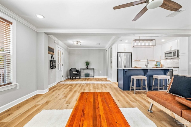 living room featuring crown molding, ceiling fan, and light hardwood / wood-style floors