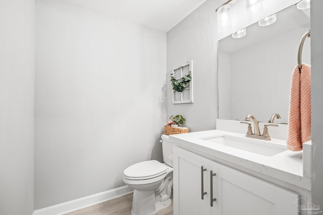 bathroom with wood-type flooring, vanity, and toilet