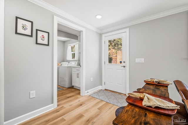 entrance foyer featuring light wood-type flooring, ornamental molding, and washer and dryer