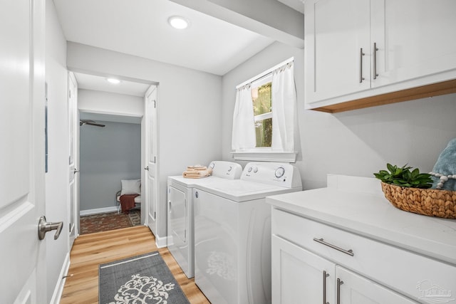 laundry area with independent washer and dryer, cabinets, and light hardwood / wood-style flooring