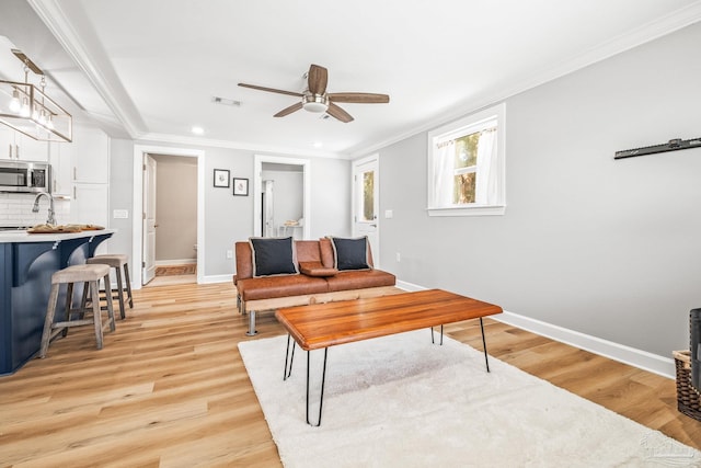 living room featuring crown molding, ceiling fan, and light hardwood / wood-style floors