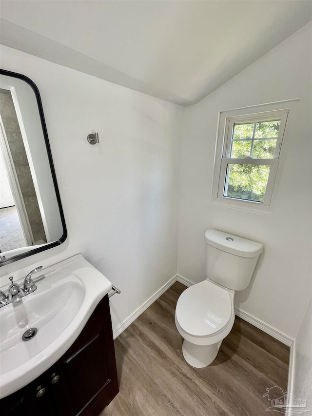 bathroom featuring vanity, lofted ceiling, hardwood / wood-style flooring, and toilet