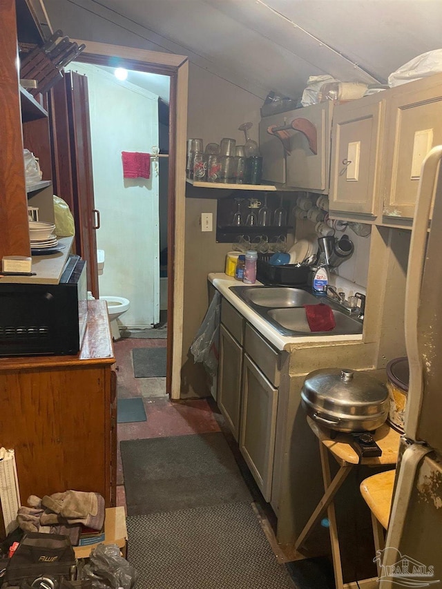 kitchen with lofted ceiling, black microwave, a sink, light countertops, and freestanding refrigerator