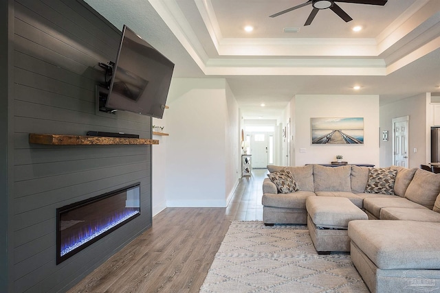3564 Sailfish Dr, Gulf Breeze, FL 32563 - living area featuring a raised ceiling, ceiling fan, a glass covered fireplace, wood finished floors, and ornamental molding