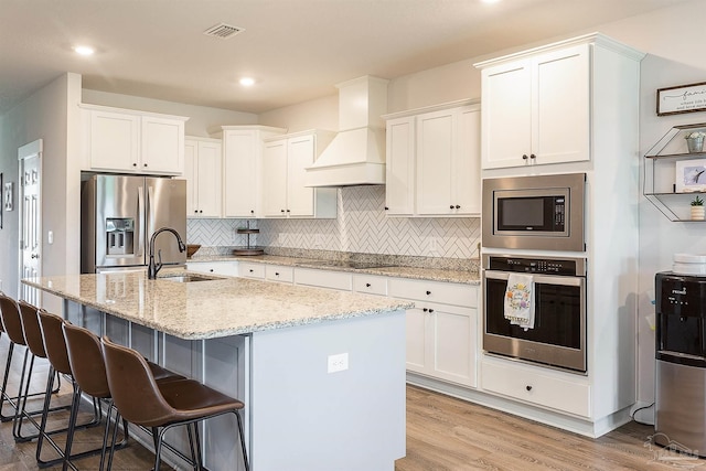 3564 Sailfish Dr, Gulf Breeze, FL 32563 - kitchen featuring appliances with stainless steel finishes, a breakfast bar, premium range hood, white cabinetry, and decorative backsplash
