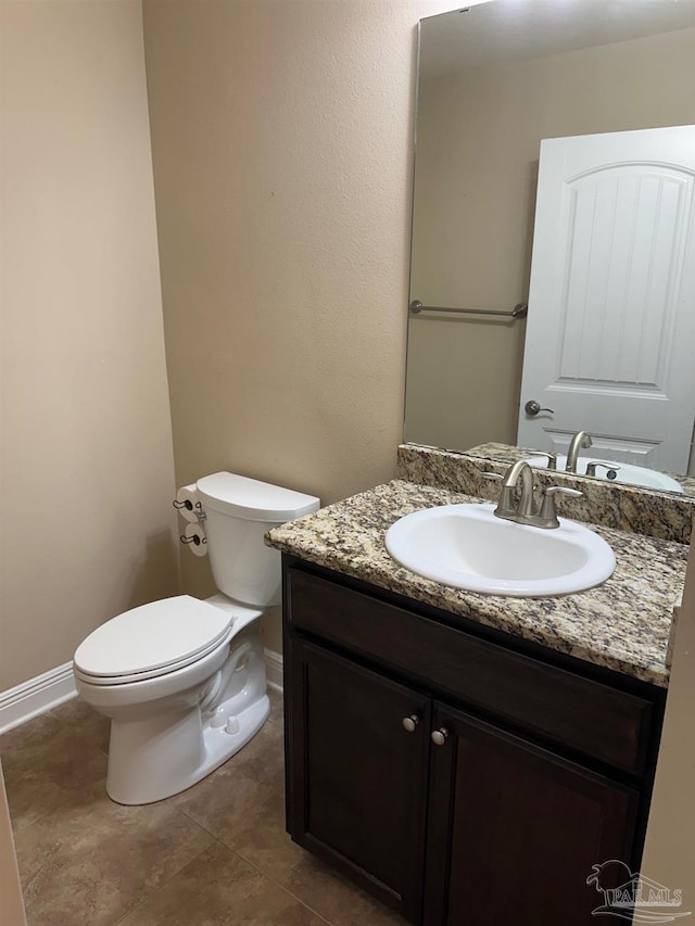 bathroom with toilet, vanity, baseboards, and tile patterned floors