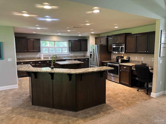 kitchen with stainless steel appliances, a kitchen island, dark brown cabinets, a kitchen breakfast bar, and recessed lighting