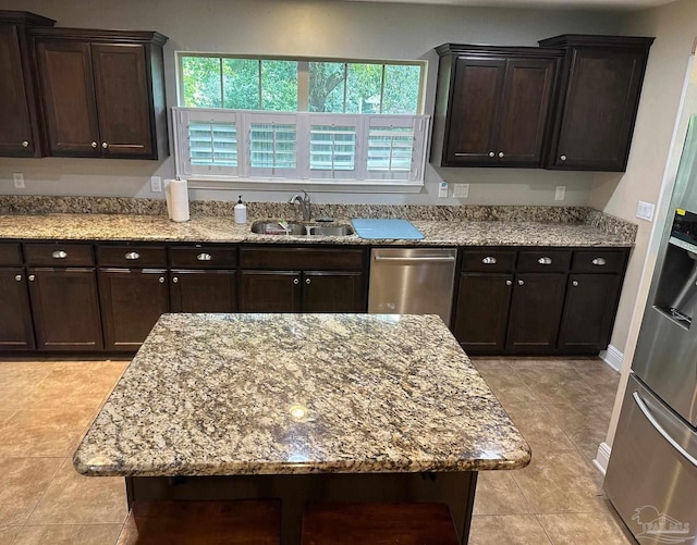 kitchen featuring a sink, stainless steel appliances, light stone counters, and light tile patterned flooring