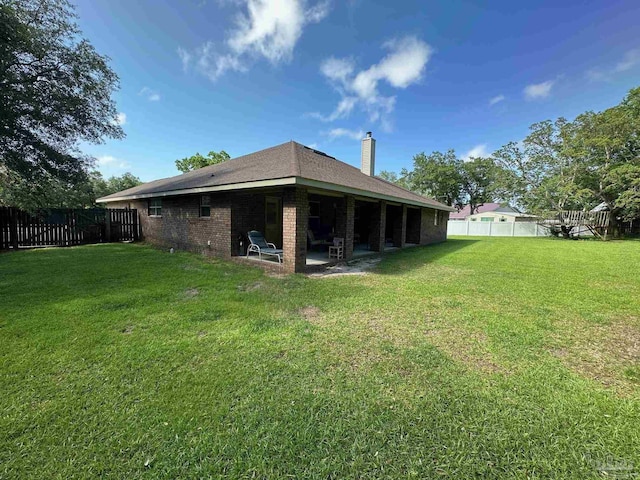 back of house featuring a chimney, brick siding, and a patio