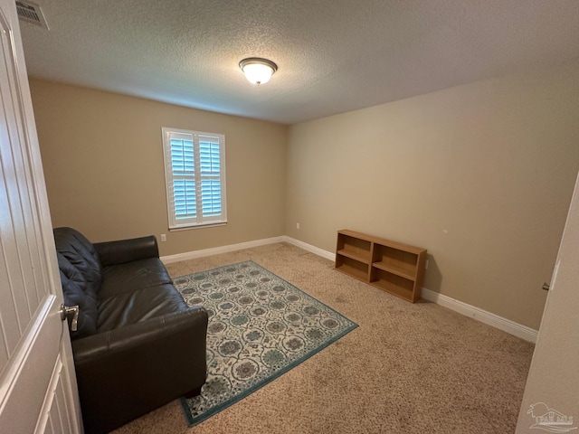 living area with carpet, a textured ceiling, and baseboards
