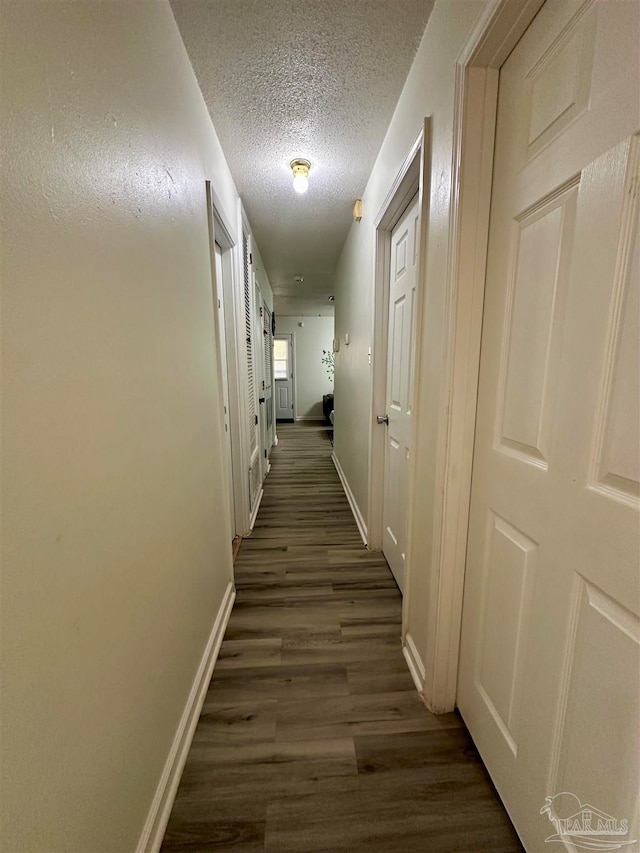 hall featuring a textured ceiling and dark wood-type flooring