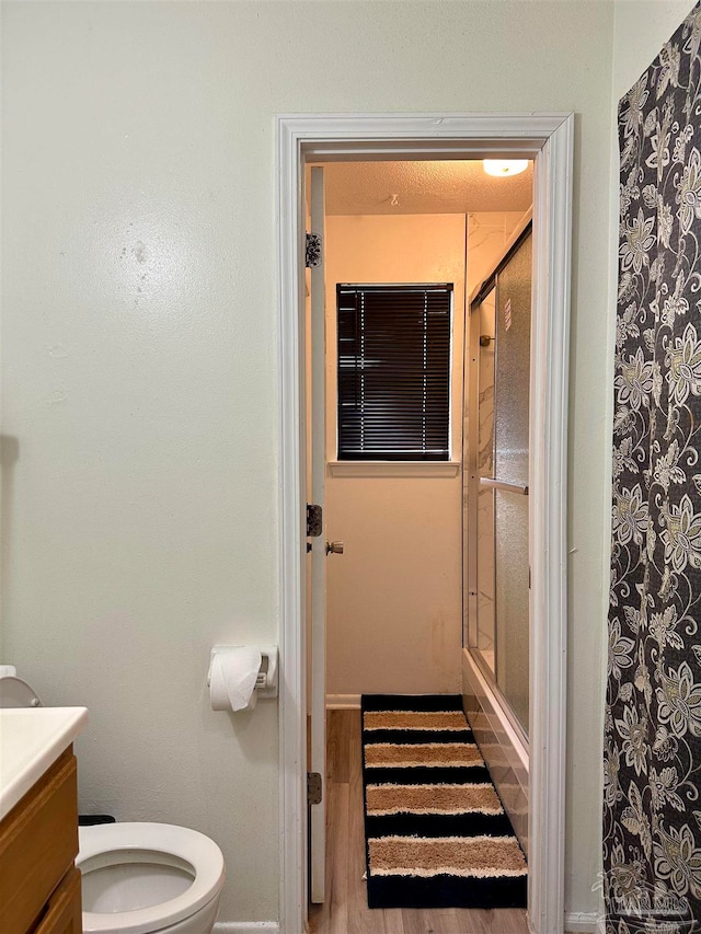 bathroom with wood-type flooring, a shower with curtain, vanity, and toilet