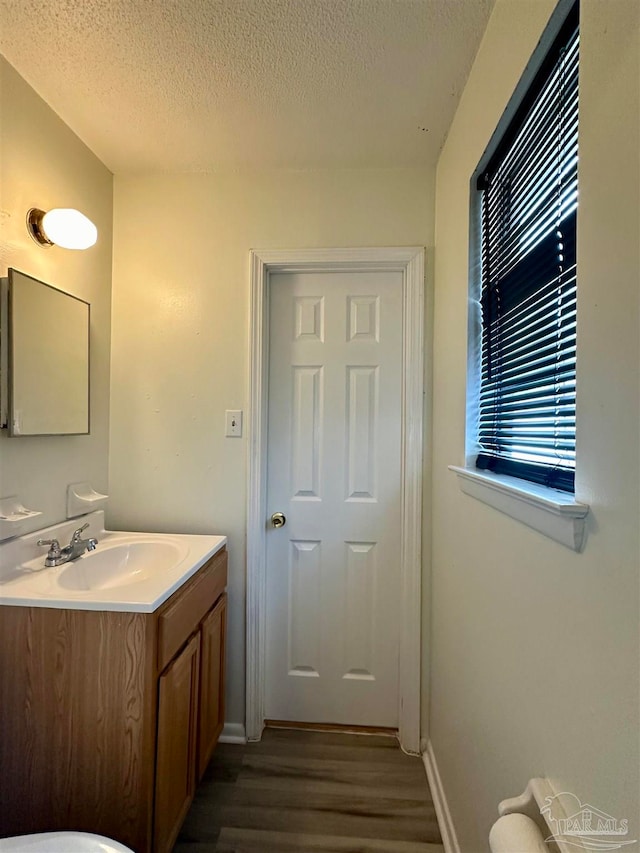 bathroom with a textured ceiling, vanity, and hardwood / wood-style floors