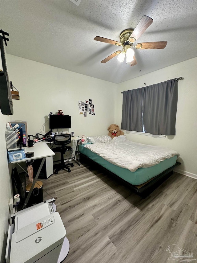 bedroom with ceiling fan, a textured ceiling, and wood-type flooring