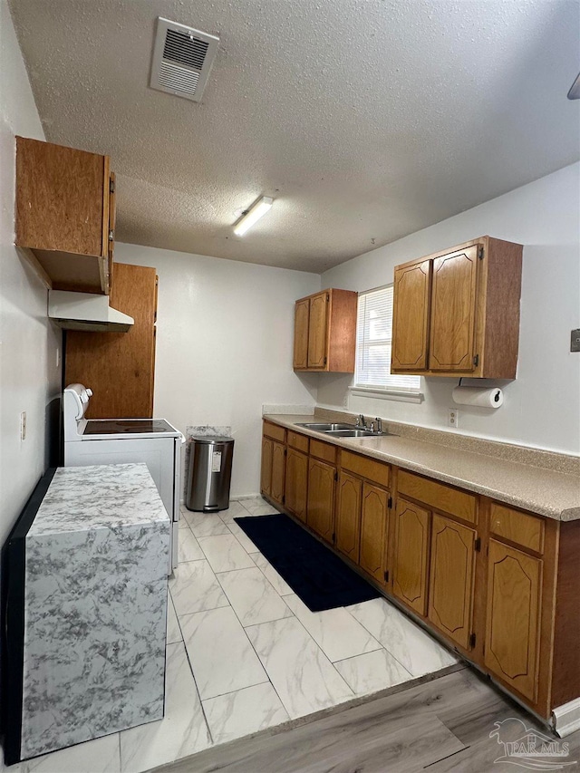 kitchen featuring a textured ceiling, stove, and sink