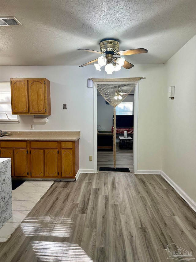 kitchen featuring ceiling fan, a textured ceiling, and light hardwood / wood-style flooring