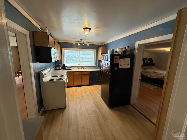 1159 Twin Bridges Rd, Flomaton, AL 36441 - kitchen with freestanding refrigerator, white electric range, light wood finished floors, light countertops, and brown cabinets