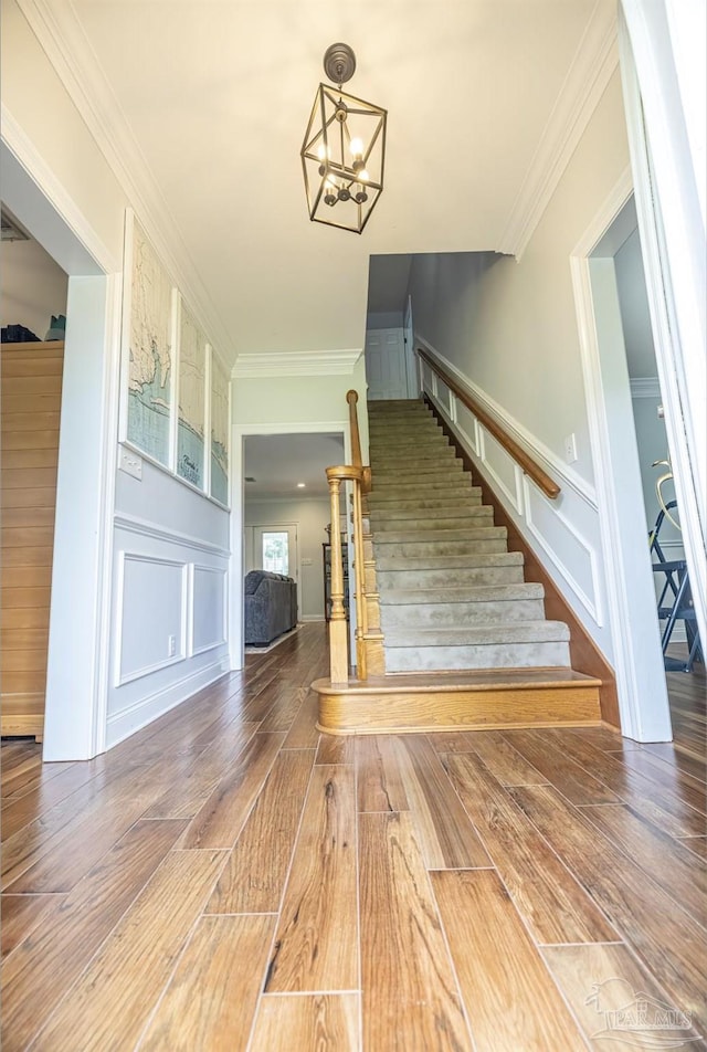 5013 Roland Rd, Pace, FL 32571 - staircase with a decorative wall, wood finished floors, a chandelier, and crown molding